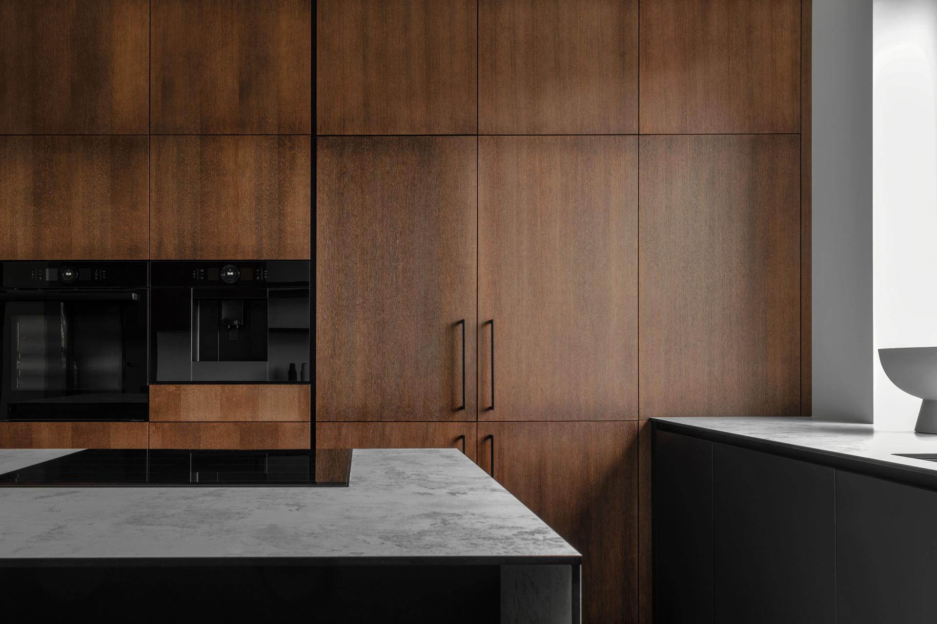 Modern minimalistic kitchen with black and wooden surfaces, marble kitchen island top and household appliances. Modern Concept For Interior Design And Architecture.