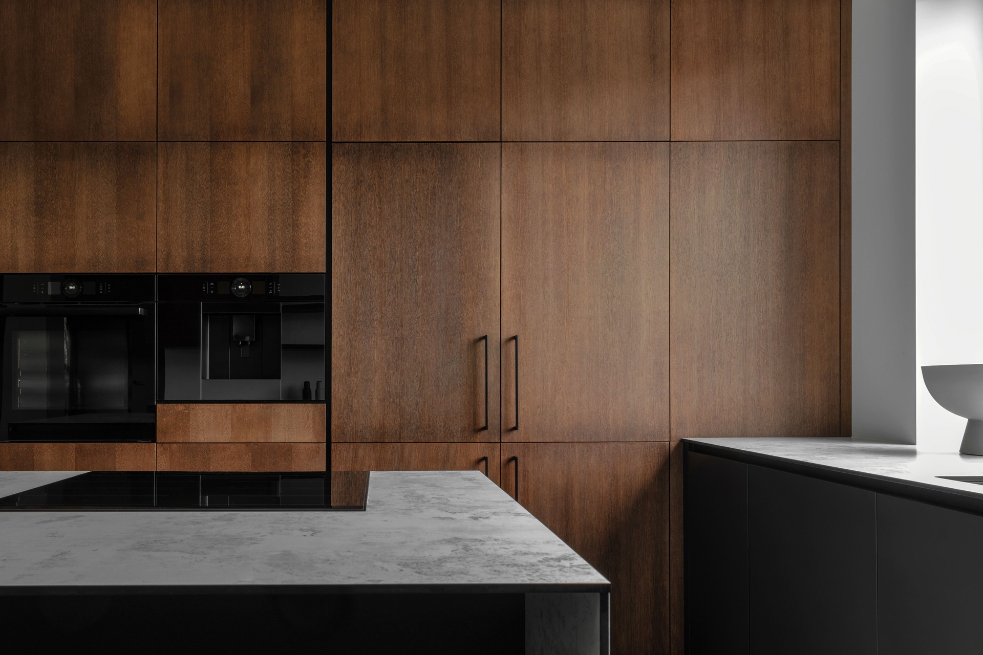 Modern minimalistic kitchen with black and wooden surfaces, marble kitchen island top and household appliances. Modern Concept For Interior Design And Architecture.