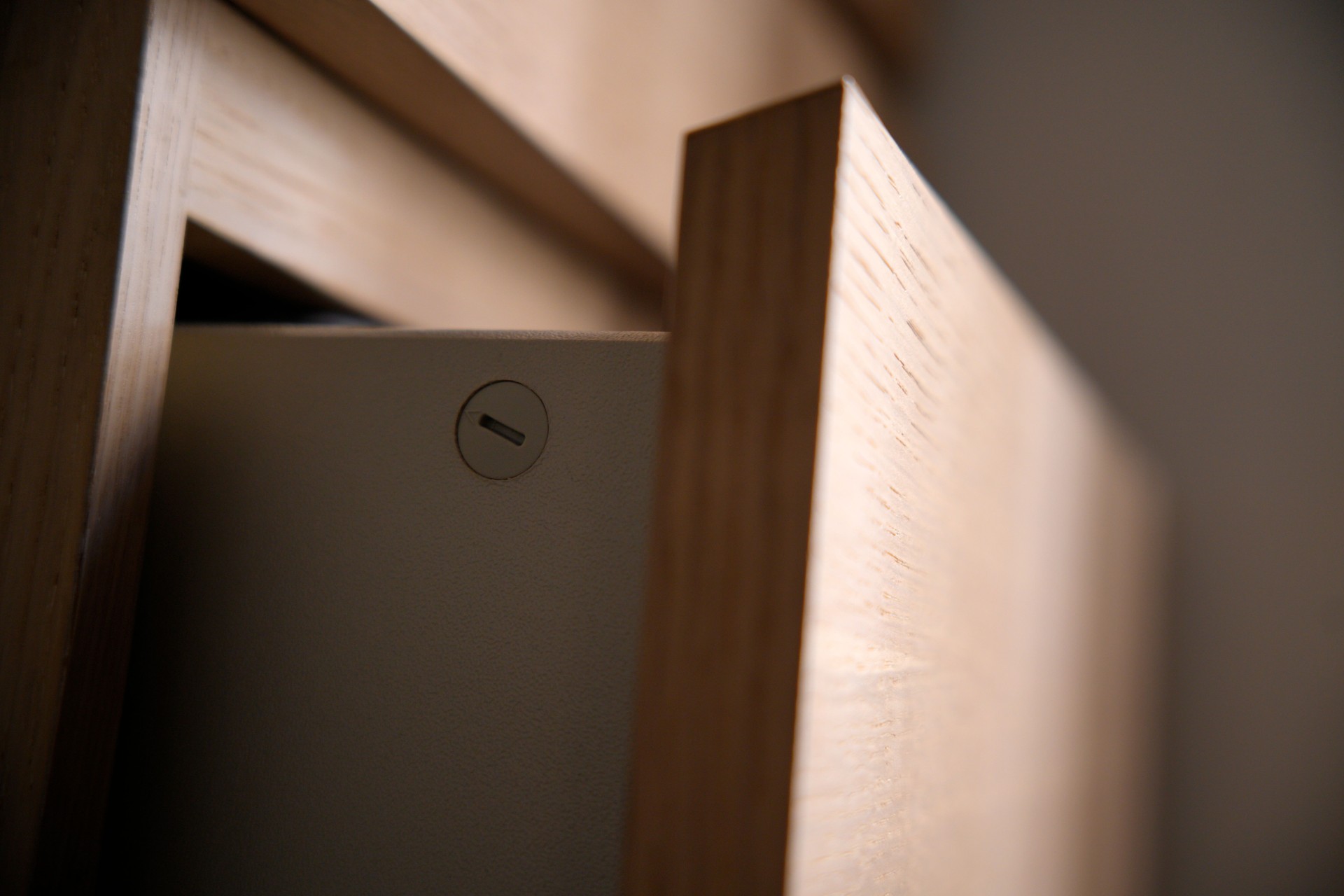 Wooden cabinet door partially covering drawer with keyhole